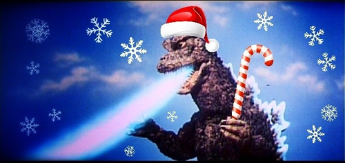 Fire-breathing Godzilla wearing a Santa hat and holding a candy cane. [Formatted]